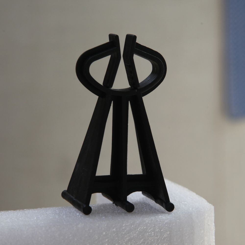 Black clip spacer with a snap-fit jaw and splayed legs