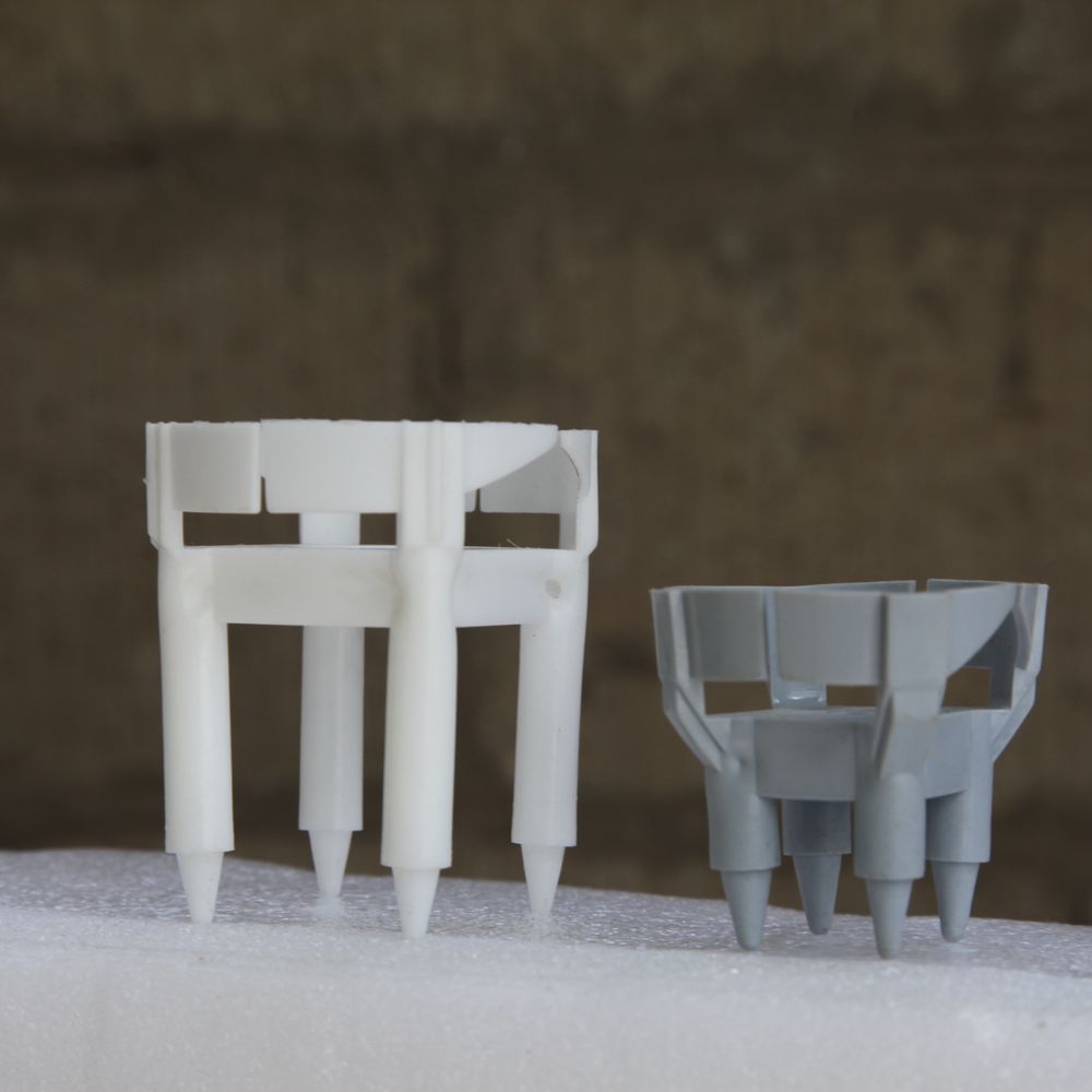 Two Praxifix four-leg spacers in white and grey polymer